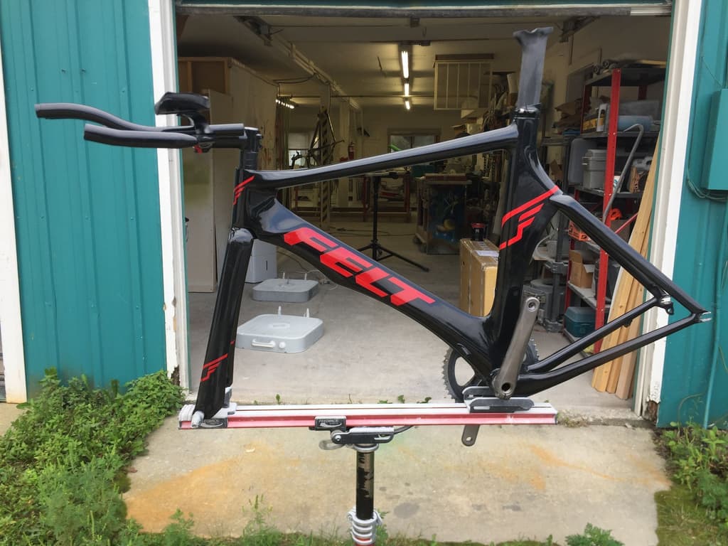 Time trial frame refinished in black and red, photographed at the shop entrance.