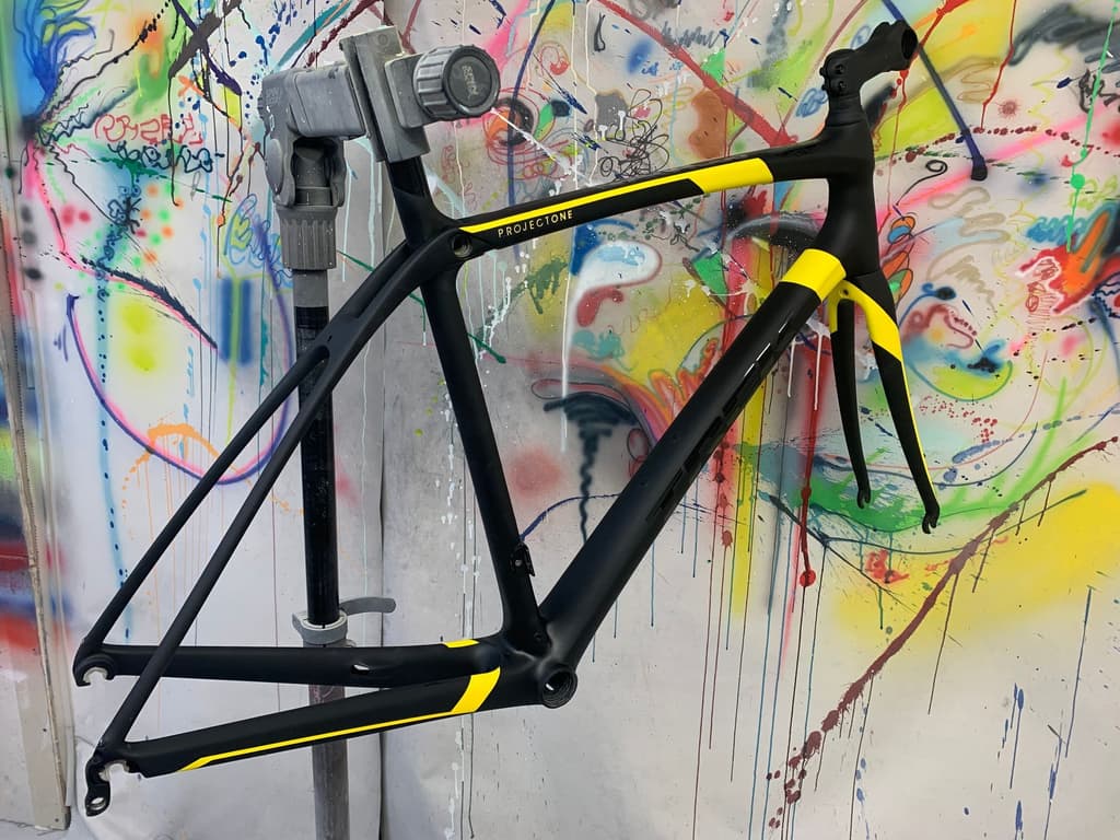 Road frame refinished in matte black with bright yellow accent panels and "Project One"-style lettering reproduced on the top tube.