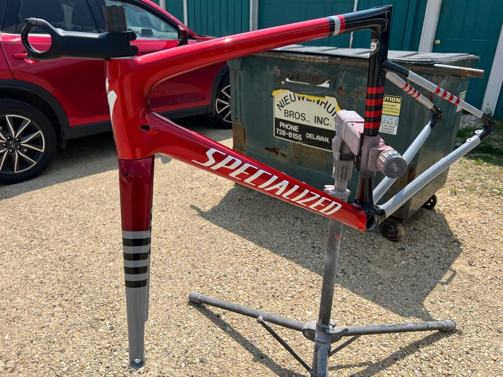 Specialized road frame refinished in gloss red with black-and-white striped panels on the head tube and fork legs, photographed outside the shop.