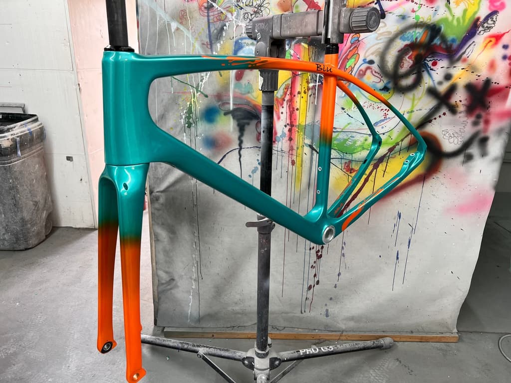 Road frame finished with a two-tone fade from teal to orange, personalized with the name "Blu" on the top tube.