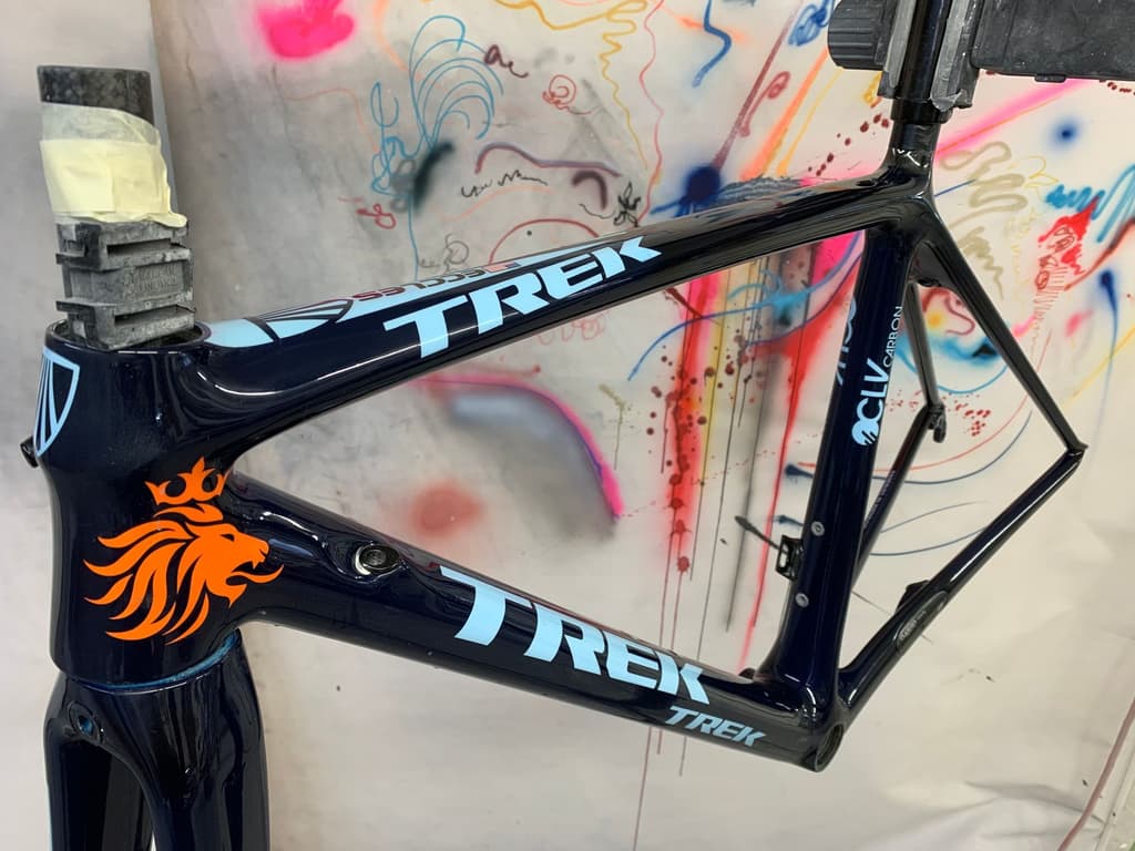 Trek OCLV Carbon road frame refinished in gloss navy blue with a custom orange lion-crest decal added to the head tube.